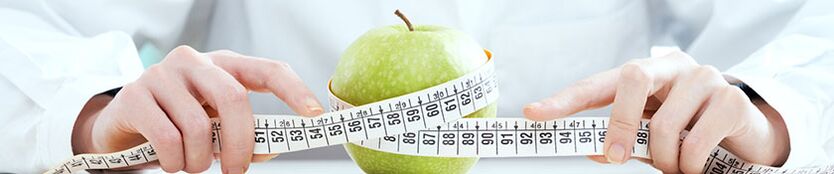 La niña mide la manzana con una cinta de centímetro